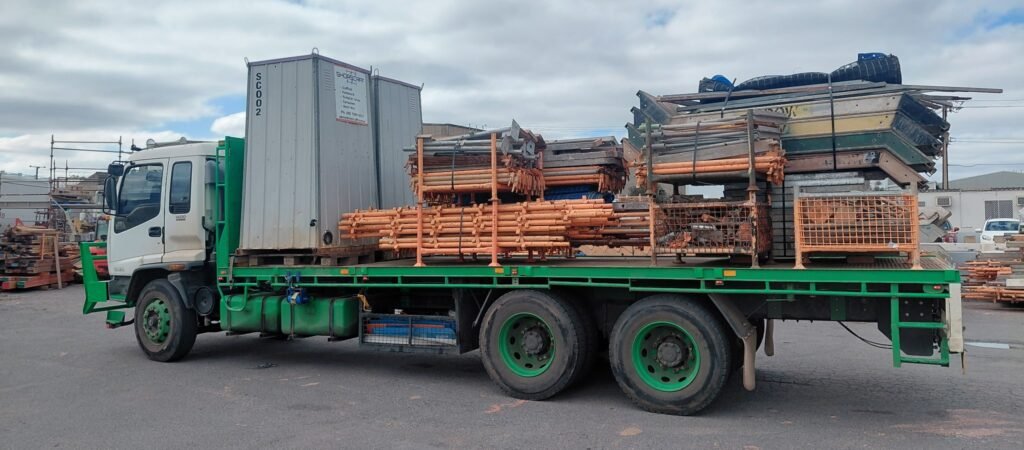 Flatbed Truck Loaded With Portaloo And Scaffold1 1024x450